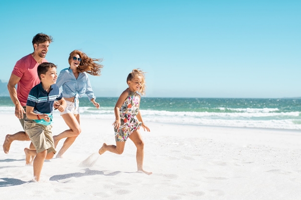 happy family running along the beach while on summer vacation